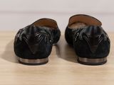 pair of black shoes on a wooden table with a white wall in the background