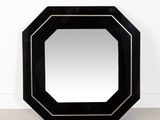 un miroir noir posé sur un sol en béton, près d'un mur blanc