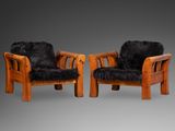 deux chaises en bois recouvertes de fourrure noire, sur fond gris