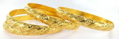 three gold wedding rings on a white surface with a white background