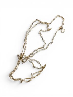 un gros plan d'un collier avec une chaîne posé sur une surface blanche
