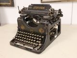 an old typewriter sitting on a table in front of a painting