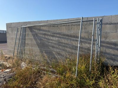 une clôture située à côté d'un bâtiment surmonté d'une clôture