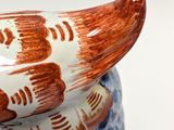 a blue and white vase with a banana on top of it