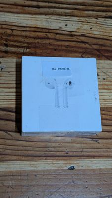 Des AirPods de la marque Apple sont posés sur une boîte, posée elle-même sur un parquet.