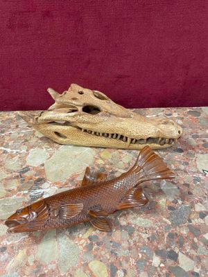 a fish statue on a table next to a piece of driftwood