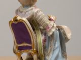 a figurine of a woman sitting on a chair