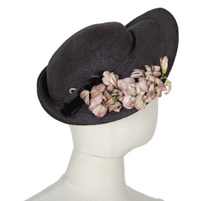 un chapeau noir orné de fleurs, posé sur la tête d'un mannequin