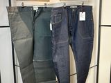 trois paires de jeans suspendues à un portant dans un magasin de vêtements