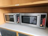 two microwaves sitting on top of a shelf next to each other