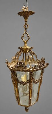an antique brass hanging light fixture with a bird on top