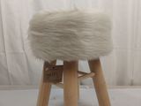 un tabouret en peau de mouton blanche avec des pieds en bois, sur fond blanc