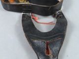 Deux morceaux de cuir sont posés sur une surface blanche ; l'un est muni d'un collier en cuir et l'autre d'une ceinture en cuir avec une boucle en laiton.