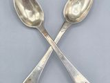 une paire de cuillères en argent posées l'une sur l'autre sur une table