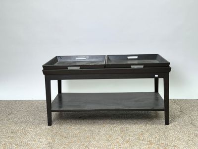 une table basse noire sur laquelle sont posés deux plateaux