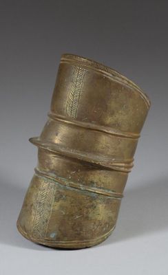 an old brass vase with a curved top sitting on top of a table