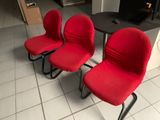 three red chairs that are sitting on a tile floor