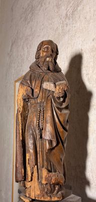 une statue représentant un homme tenant un livre dans une pièce