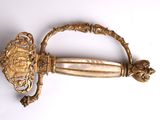 a gold sword that is on display on a white surface