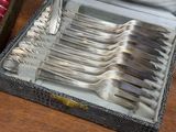 silverware in a silver case on a table with a red cloth