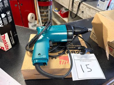 une perceuse électrique bleue posée sur une boîte