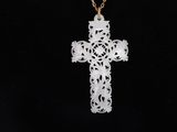 a white cross pendant with a gold chain on a black background