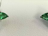 une paire de boucles d'oreilles ornées de pierres vertes sur un fond blanc