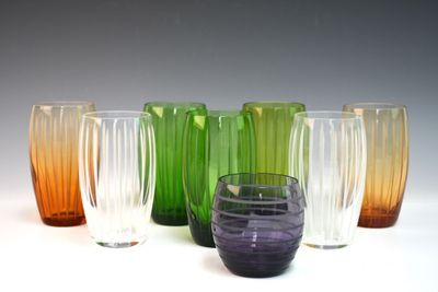 plusieurs vases en verre de différentes couleurs sont alignés sur une surface blanche