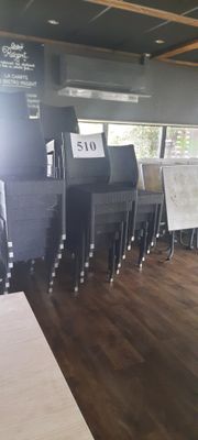 Dans un restaurant, des tables et des chaises sont alignées, et un menu est affiché au mur.