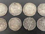 six silver coins of different sizes and shapes on a black surface