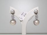 une paire de boucles d'oreilles en perles et diamants exposée dans une bijouterie
