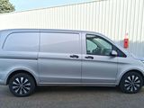 La camionnette argentée est garée devant un immeuble blanc.