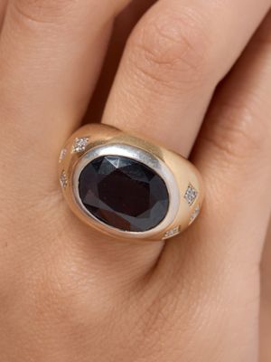 an image of a close up of a person ' s hand wearing a ring with a black stone on it