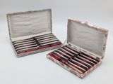 pair of silverware in a case with red and white designs