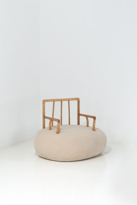 La chaise est en bois et est équipée d'un coussin beige.