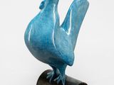 une sculpture bleue représentant un oiseau, posée sur un socle noir