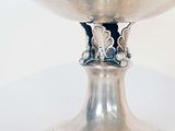 a silver bowl on a stand on a white surface