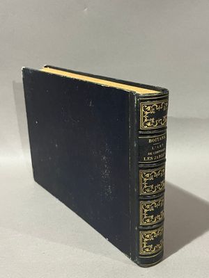 un livre noir aux bords dorés posé sur une surface blanche