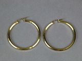 two pairs of gold hoop earrings on a white surface
