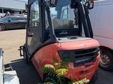 un chariot élévateur garé sur un parking à côté d'une camionnette blanche