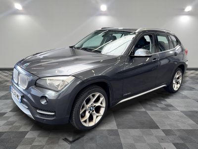 La BMW X1 est garée dans le garage, sur un sol à damier.