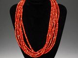 a red beaded necklace on a black mannequin