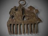 a brown metal comb with a horse and a man on it