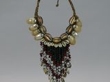 beaded necklace with shells and pearls on a stand on a white background