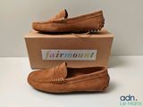 mocassins beiges avec une boîte posée sur un fond blanc