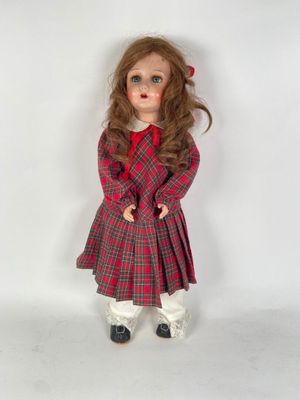 un gros plan d'une poupée portant une robe rouge et un pantalon blanc
