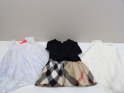 Deux robes et une robe sont posées sur une table blanche