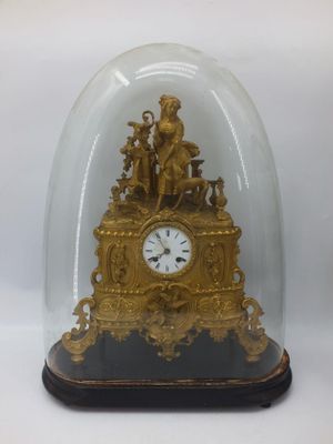 a gold clock under a glass dome on a table