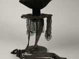 une sculpture représentant un oiseau posée sur un socle et entourée d'une chaîne