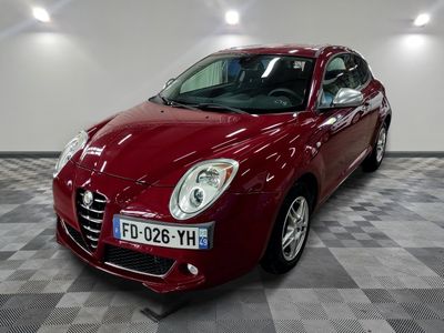 La voiture Alfa rouge est garée dans une grande pièce au sol carrelé en damier.